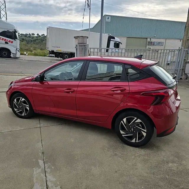 Un coche rojo está aparcado al costado de la carretera.
