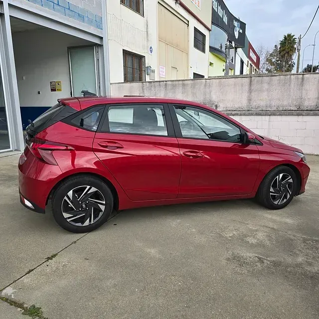 Un coche rojo está aparcado delante de un edificio.