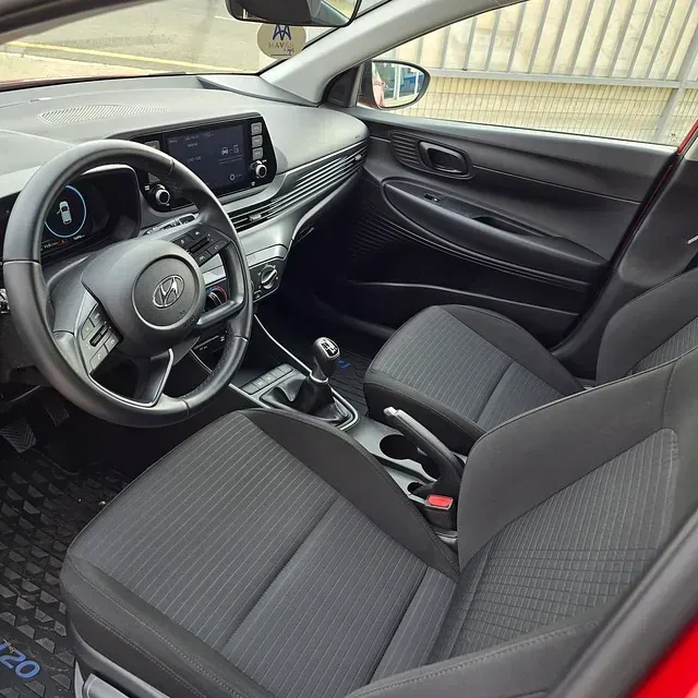 El interior de un coche rojo con asientos negros y un volante.