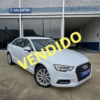 Un Audi A3 blanco está estacionado frente a un concesionario de automóviles.