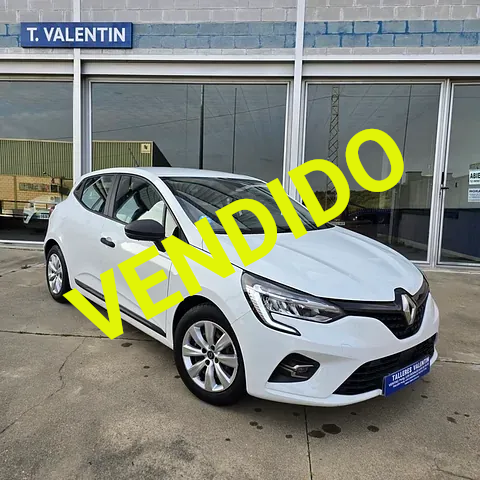 Un coche blanco está aparcado delante de un edificio que dice T. Valentin.