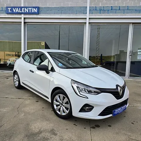 Un coche blanco está aparcado delante de un edificio que dice T. Valentin.