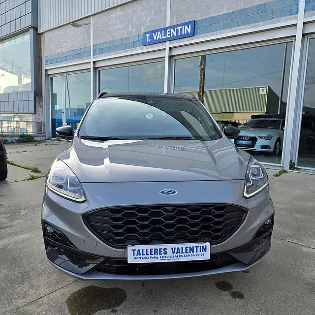 Un coche gris está aparcado delante de Talleres Valentín.