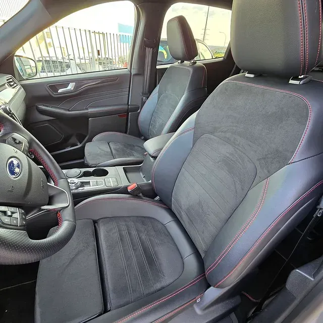 El interior de un Ford Escape con asientos negros y volante.