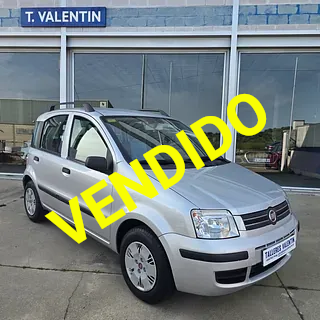 Un coche plateado está aparcado delante de un concesionario de automóviles.