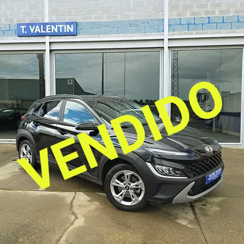 Un coche negro está aparcado delante de un concesionario de automóviles.