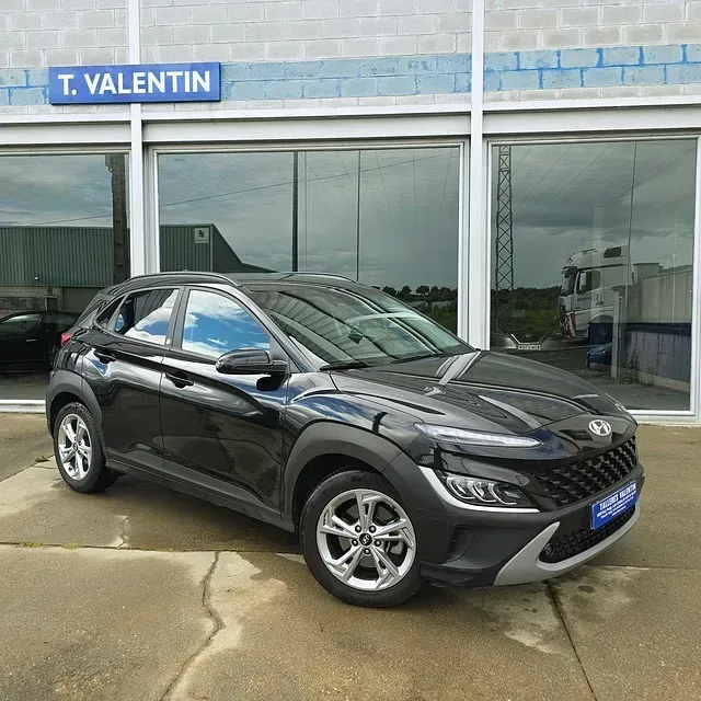 Un coche negro está aparcado delante de un concesionario de automóviles.