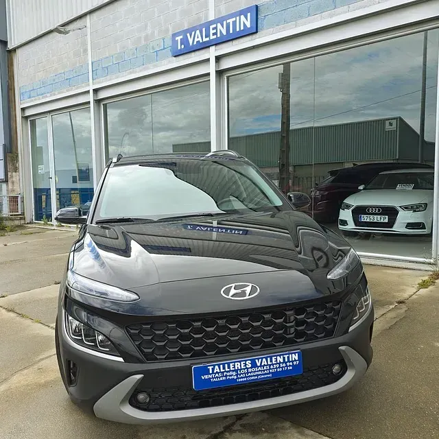 Un coche está aparcado delante de un concesionario de coches llamado talleres valentin