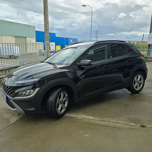 Un coche negro está aparcado delante de un edificio.