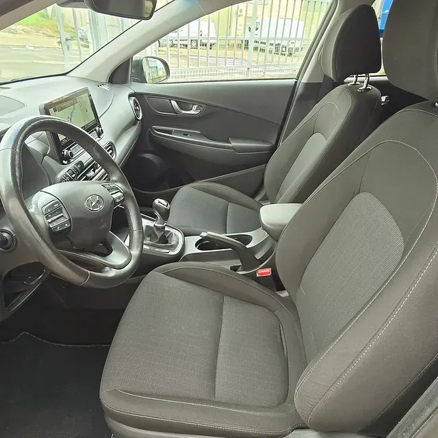 El interior de un coche con asientos negros y un volante.