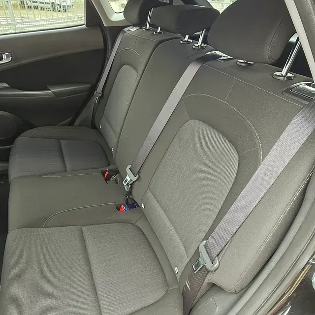 El asiento trasero de un coche con cinturones de seguridad puestos.