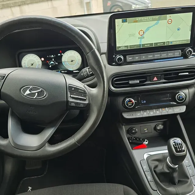 El interior de un coche con volante y sistema de navegación.