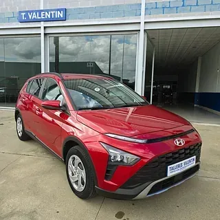 Un coche rojo está aparcado delante de un concesionario de automóviles.