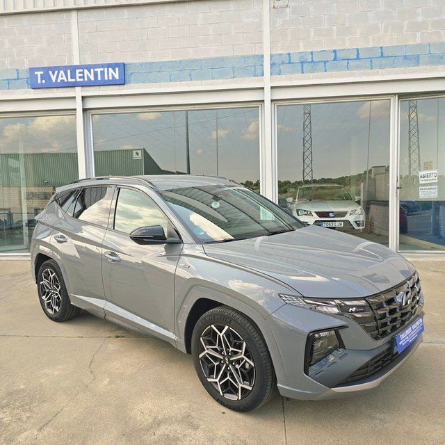 Un coche azul está aparcado delante de un concesionario de automóviles.