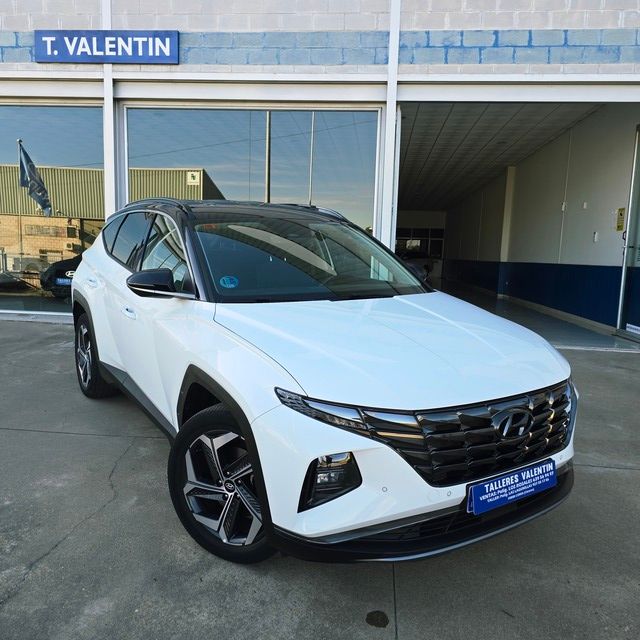 Un coche azul está aparcado delante de un concesionario de automóviles.