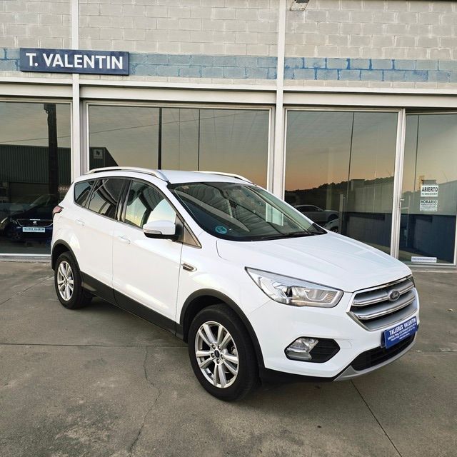 Un coche azul está aparcado delante de un concesionario de automóviles.