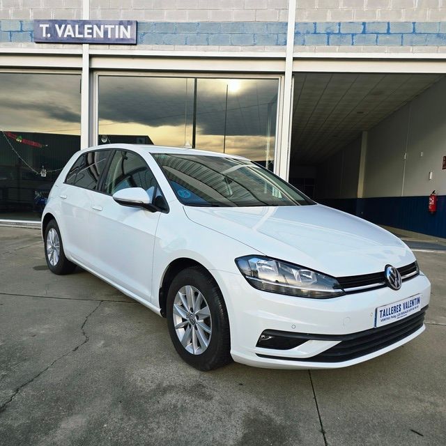 Un coche blanco está aparcado delante de un concesionario de automóviles.