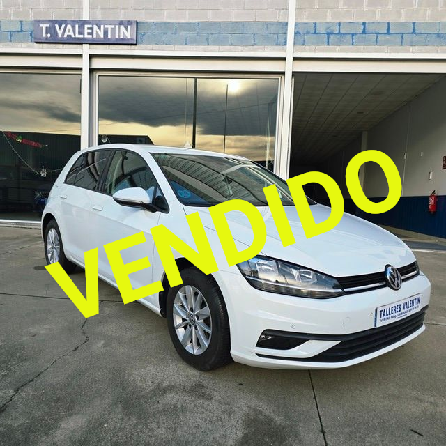 Un coche blanco está aparcado delante de un concesionario de automóviles.