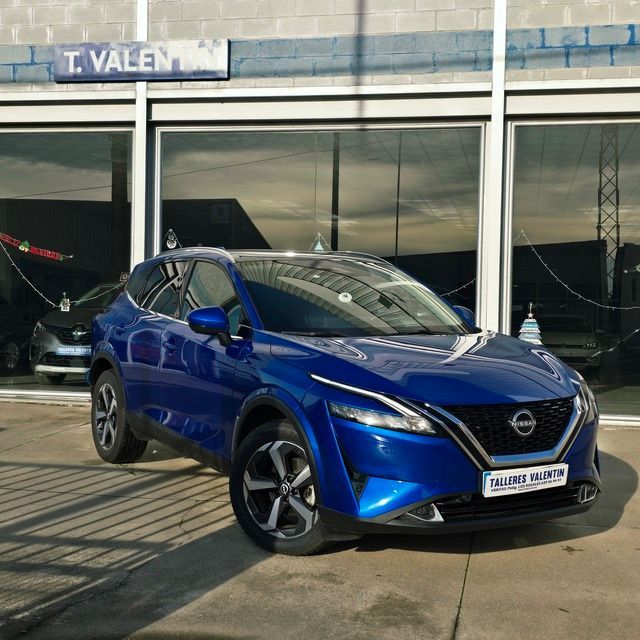 Un Ford Escape plateado está estacionado frente a un concesionario de automóviles.