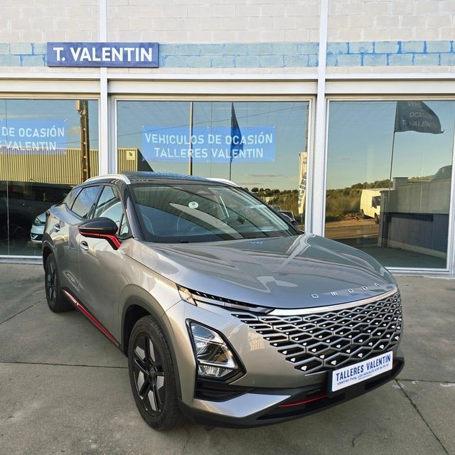 Un Nissan Qashqai plateado está estacionado frente a un concesionario de automóviles.