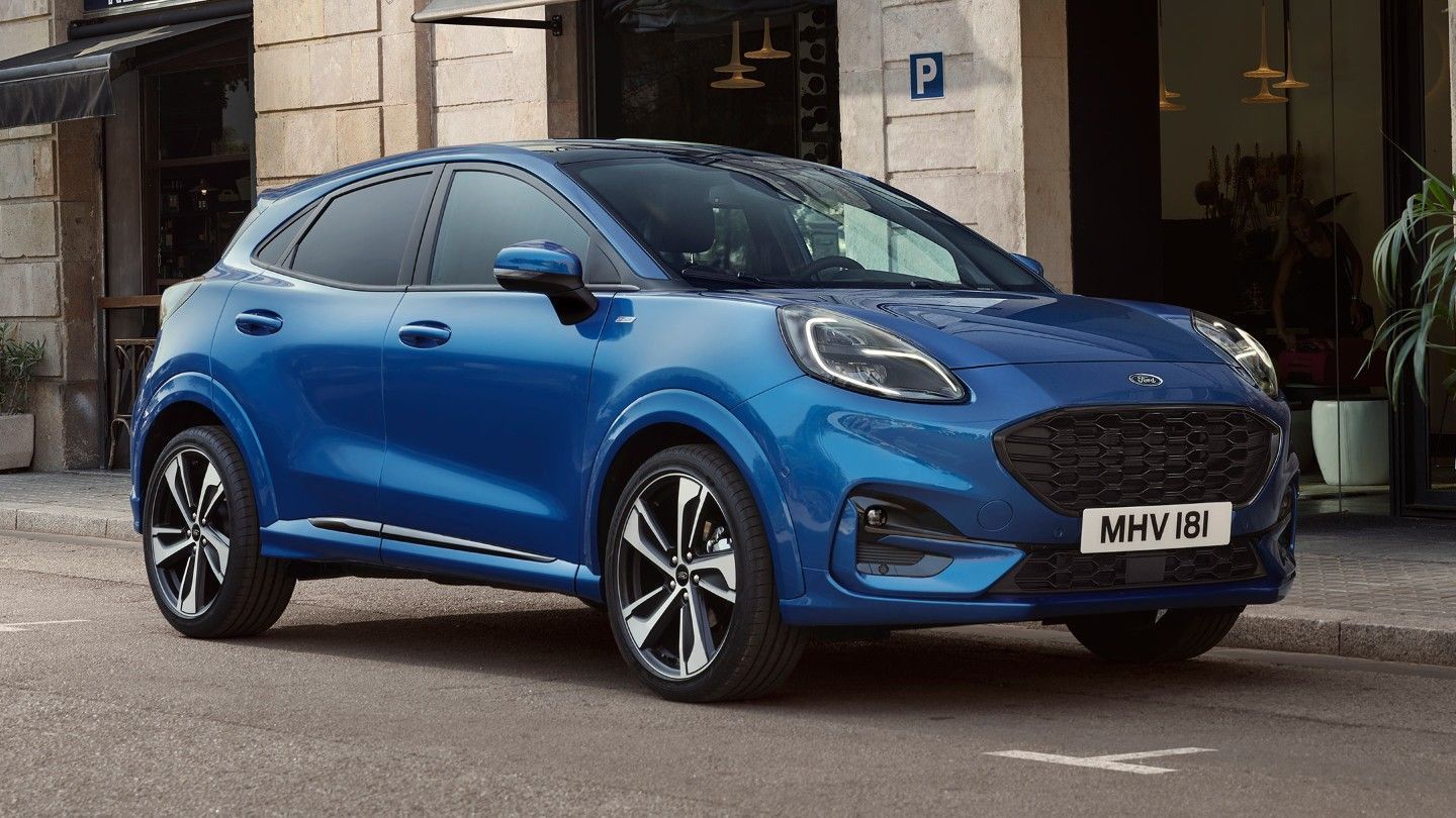 Un Ford Puma azul está estacionado frente a un edificio.