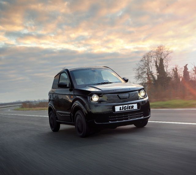 Un coche azul está aparcado delante de un concesionario de automóviles.
