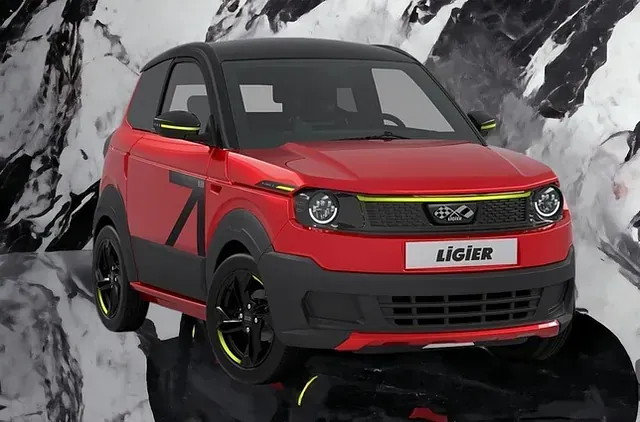 Un coche rojo está aparcado delante de una montaña.