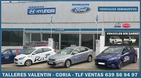 Varios coches están aparcados delante de un edificio que dice talleres valentin