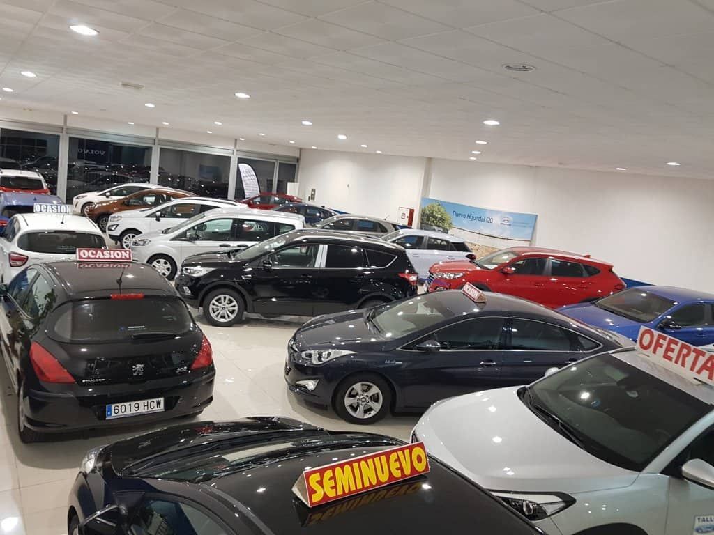 Hay muchos coches aparcados en una sala de exposición.