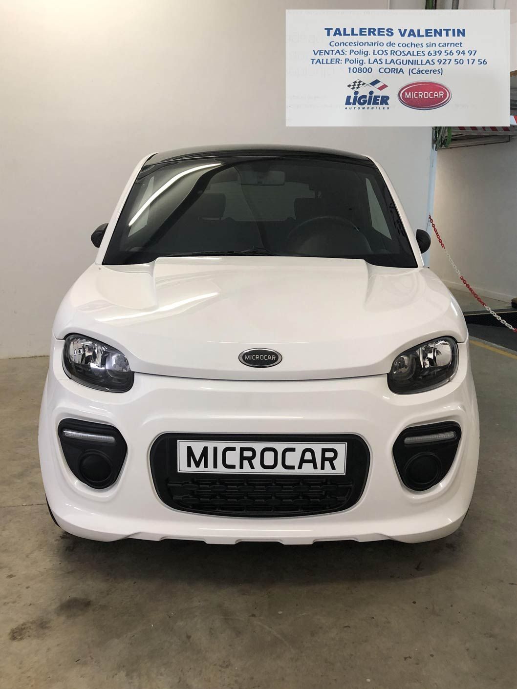 Un microcoche blanco está aparcado en un garaje.