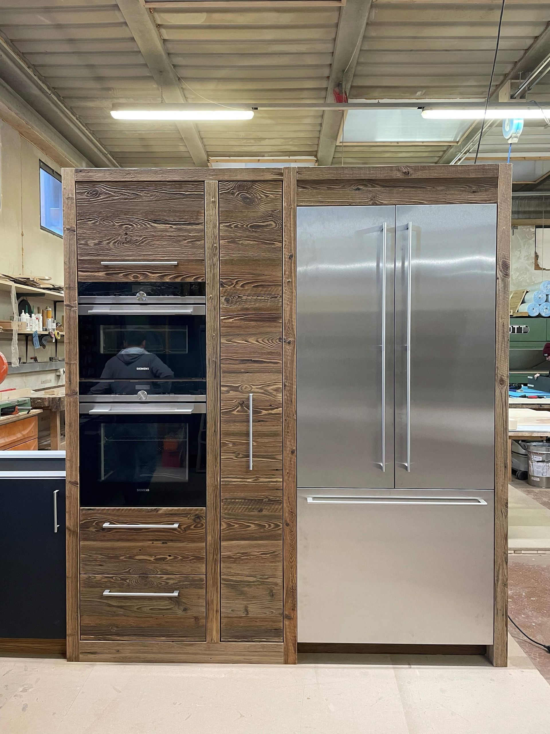 compartiment de cuisine en bois avec un four, un frigo, des tiroirs et placards.