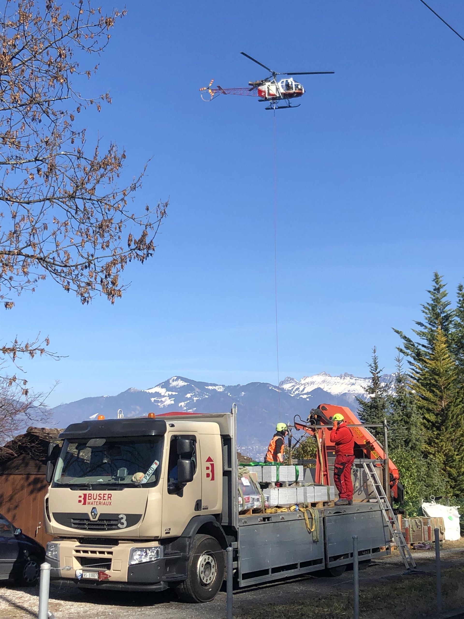 un camion grue de Buser Matériaux et un hélicoptère au dessus