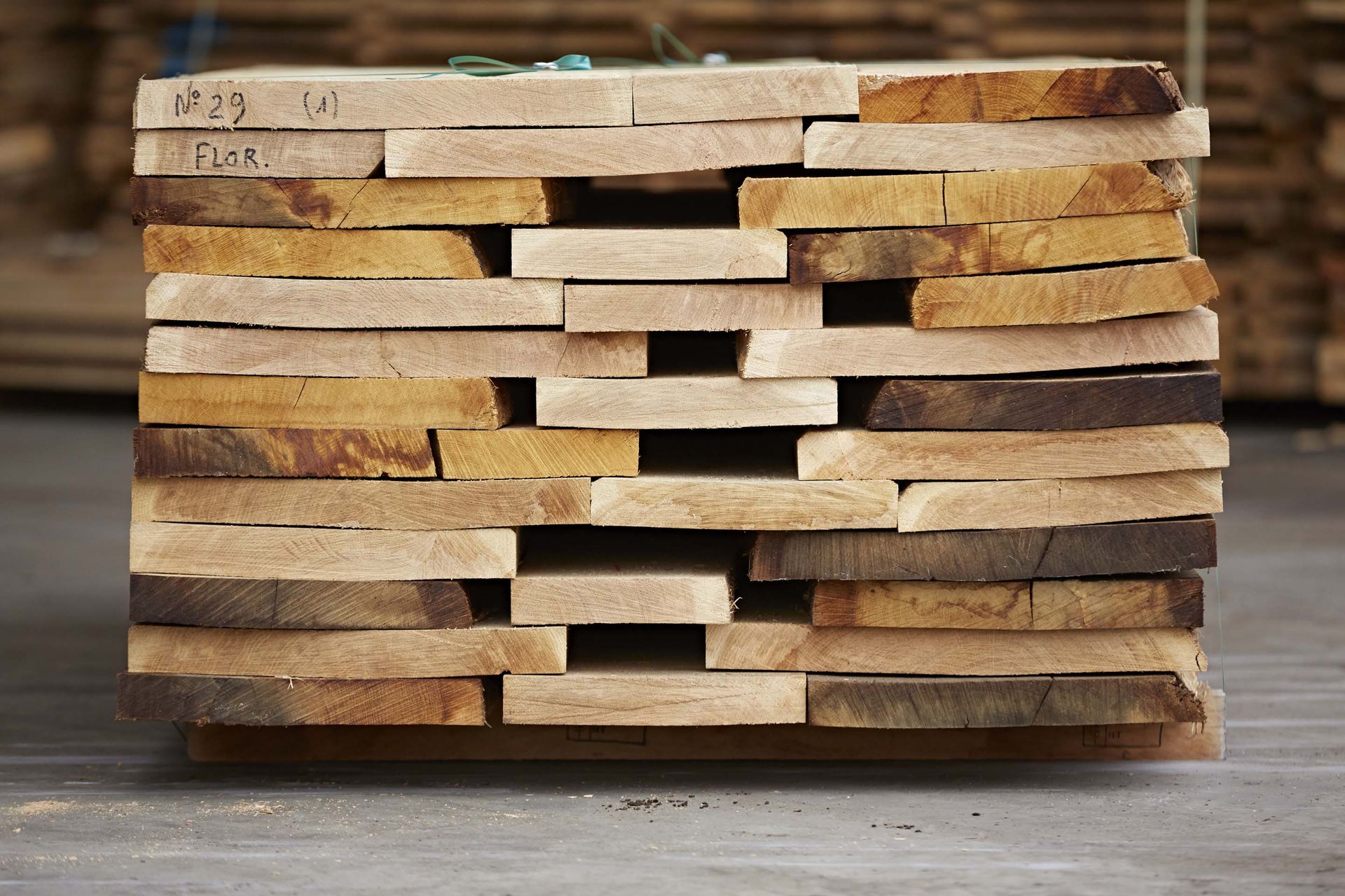 Pile de planches de bois, de couleur variant du beige clair au brun foncé, vue de l'extrémité.
