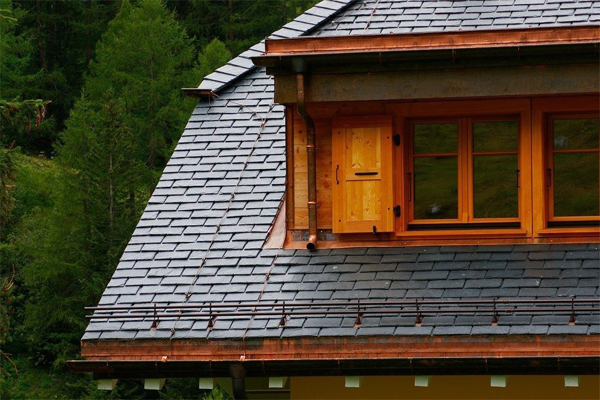 partie d'un toit en ardoise et d'une fenêtre en bois
