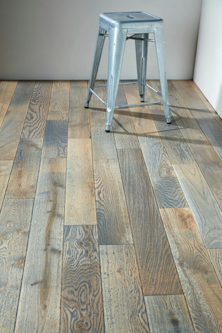 une pièce avec un parquet en bois gris et un tabouret en fer