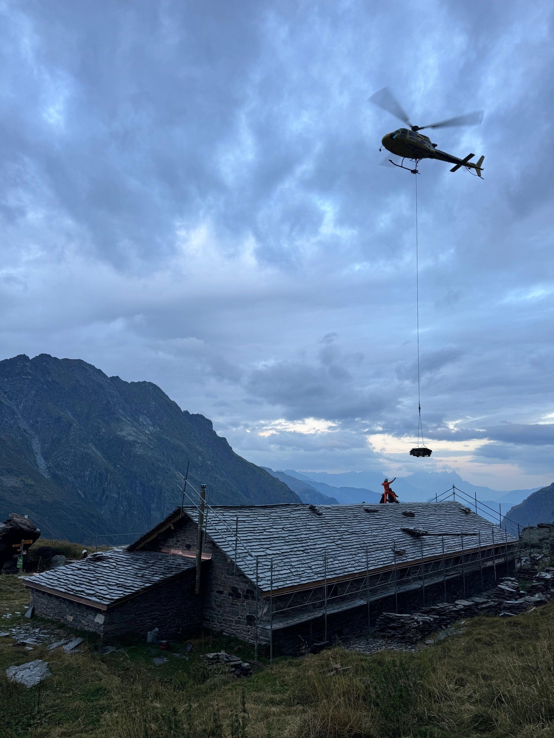 vue sur une maison survolée par un hélicoptère transportant du matériel