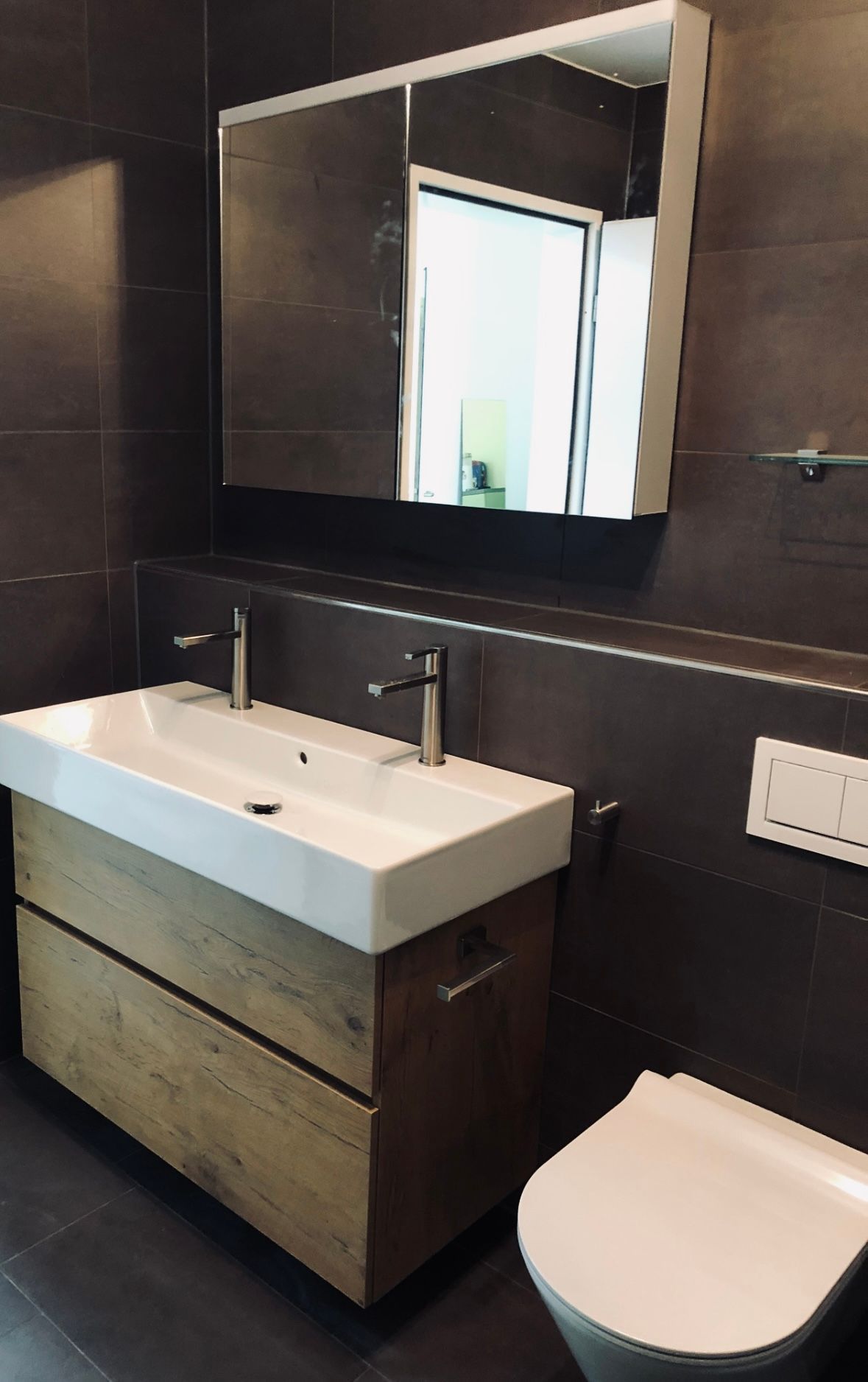 Ein Badezimmer mit Toilette, Waschbecken und Spiegel. Foto  von der Duri Haustechnik GmbH