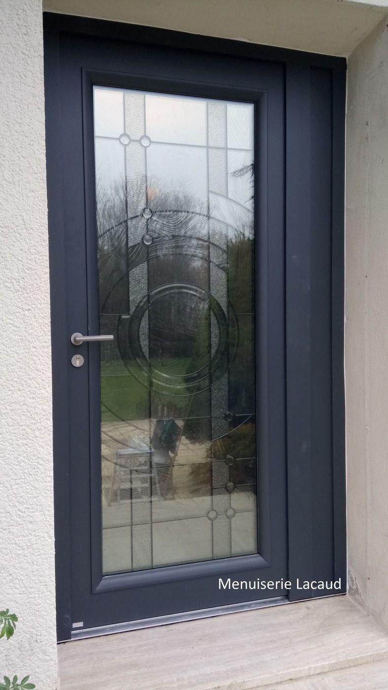 Porte d'entrée noire avec panneau en verre dépoli et poignée argentée sur une entrée de maison