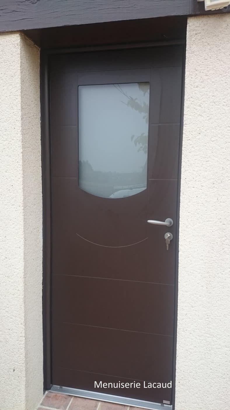 Porte d'entrée marron avec fenêtre en verre dépoli et poignée argentée dans un hall d'entrée en stuc