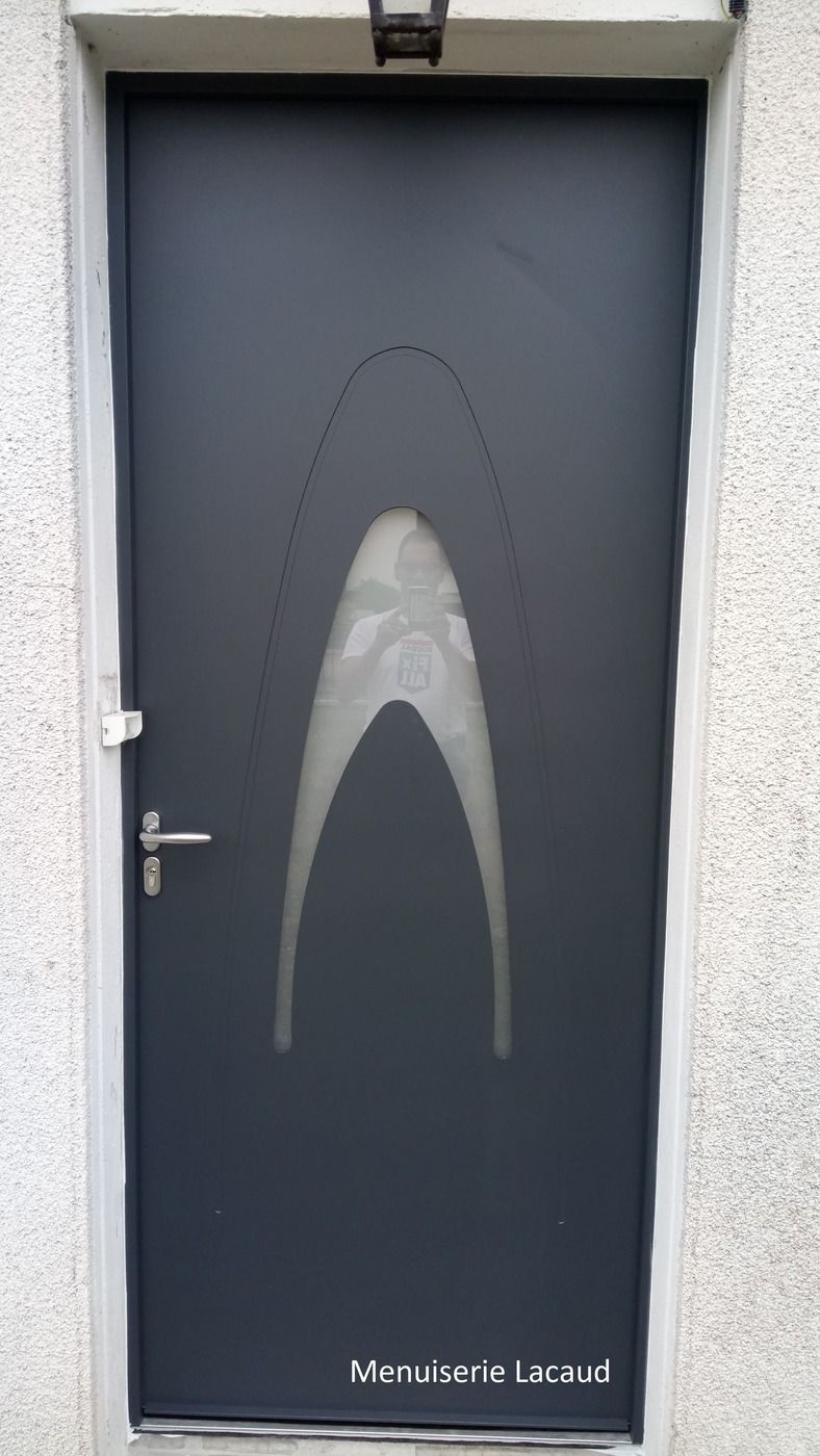 Porte gris foncé avec poignée argentée et motif d'arche blanche abstraite, inscription en bas.
