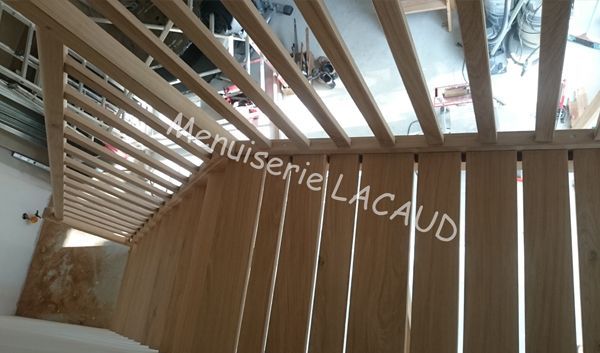 Toiture en lattes de bois avec ouvertures de puits de lumière au-dessus d'un escalier courbe ou d'un balcon intérieur