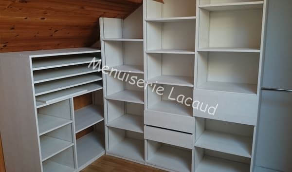 Étagères encastrées blanches dans une pièce mansardée avec un plafond en bois incliné