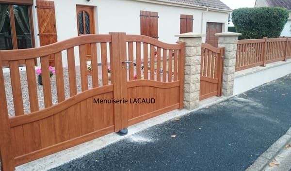 Portail et clôture en bois donnant sur un trottoir de banlieue et l'entrée de la maison