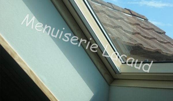 Fenêtre de toit et toit de tuiles grises sur un bâtiment bleu clair