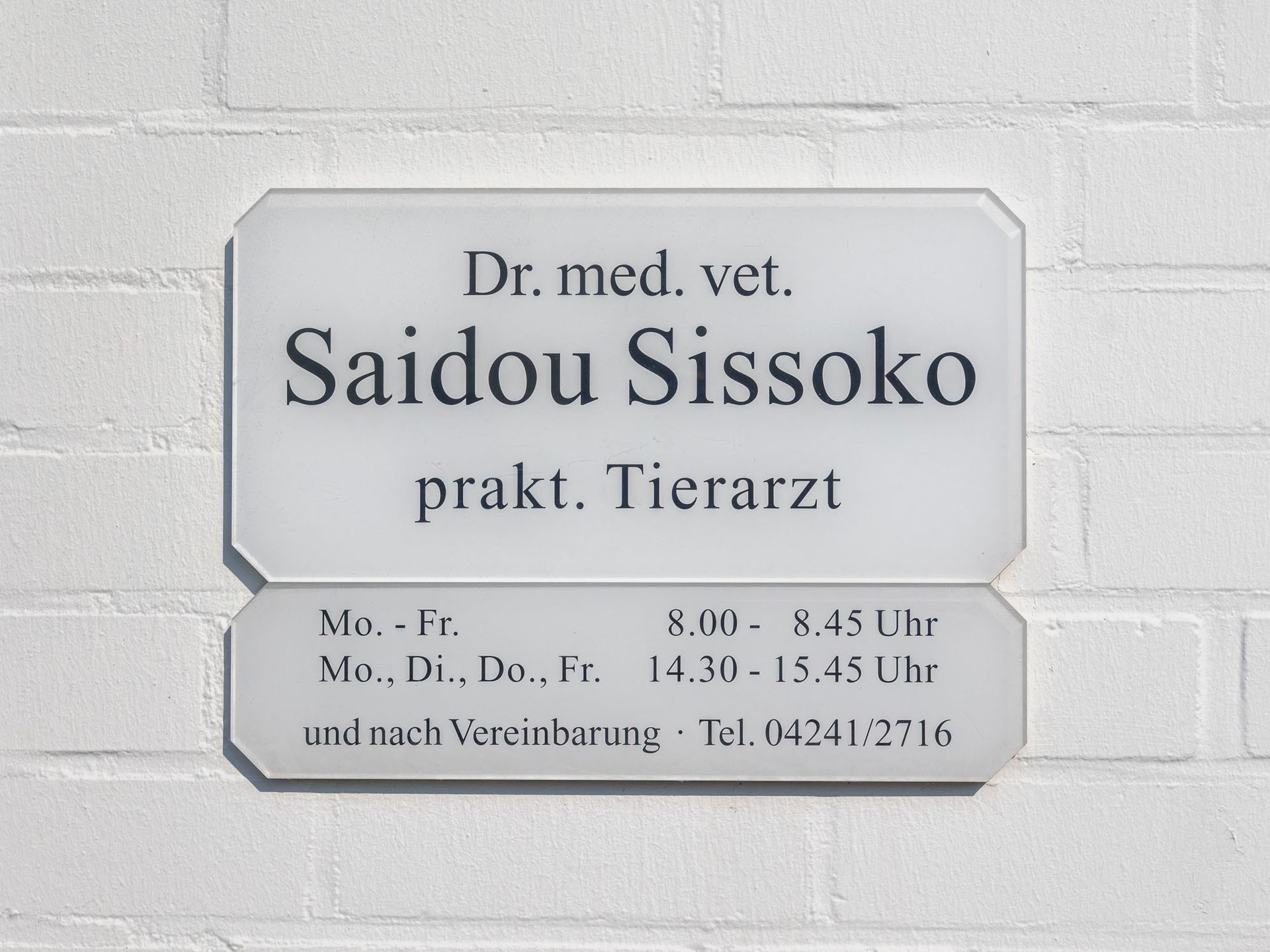 Ein Schild an einer Backsteinmauer sagt Dr. Med. Veterinär Sadou Sissoko