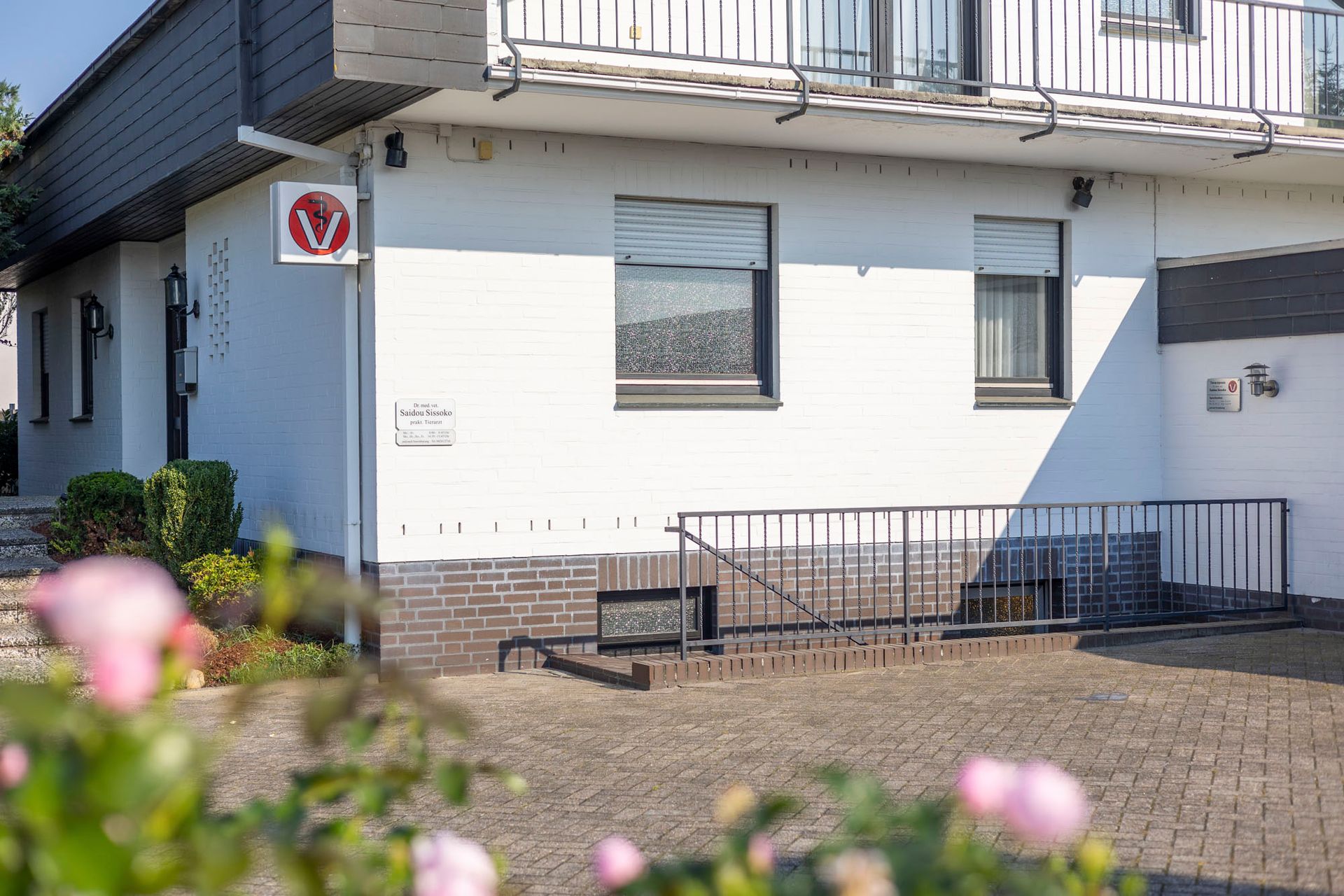 Ein weißes Haus mit einem Balkon und Blumen davor.