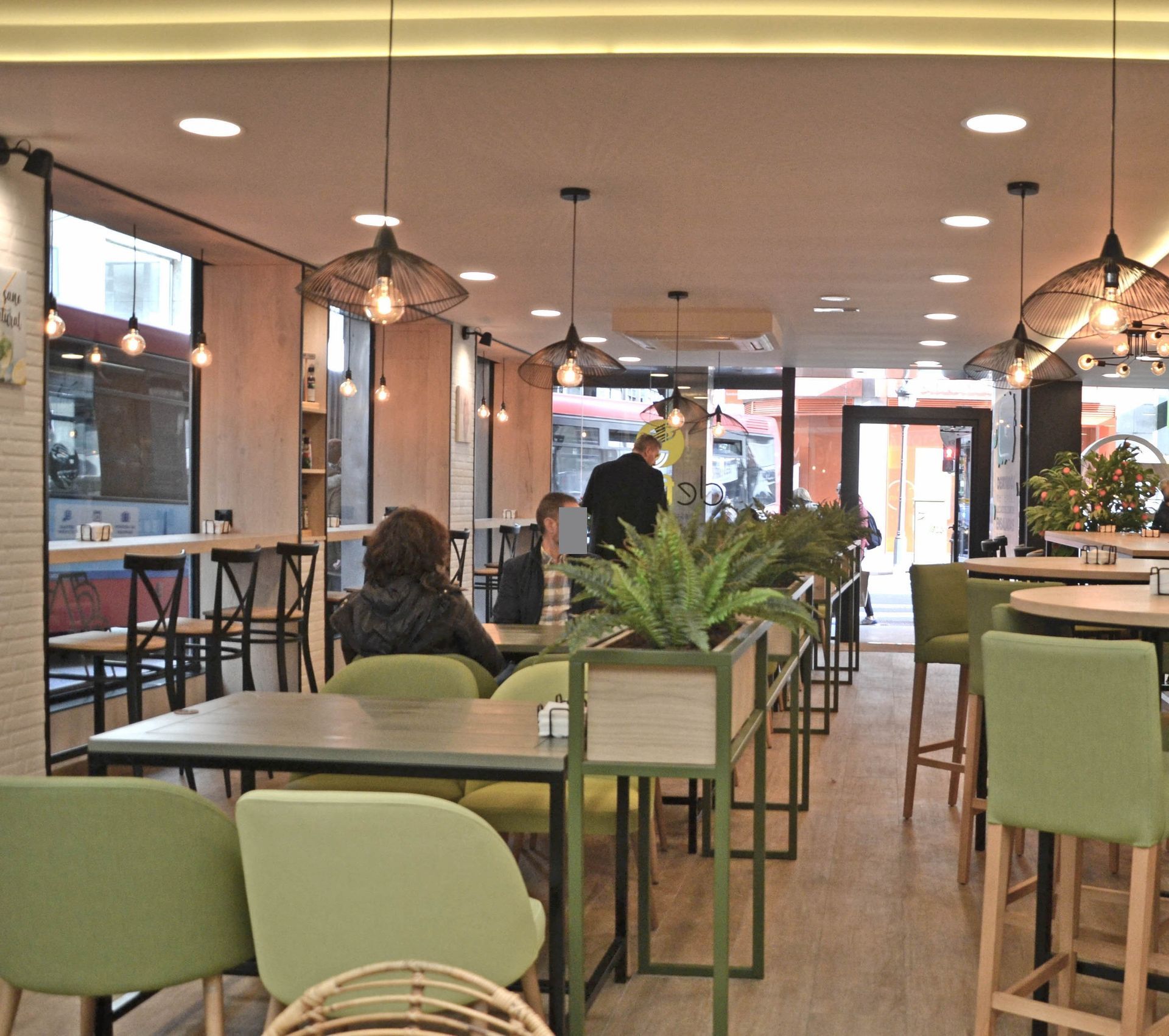 Un restaurante con sillas y mesas verdes con plantas.