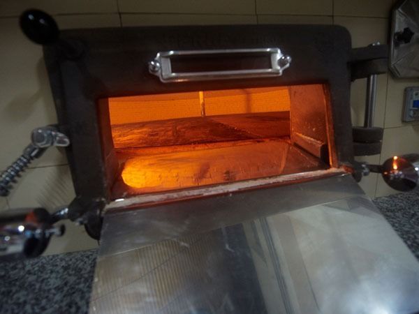 Un horno de acero inoxidable con la puerta abierta y un trozo de pan dentro.