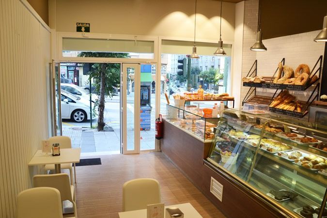 El interior de una panadería con mesas y sillas y una vitrina de cristal.