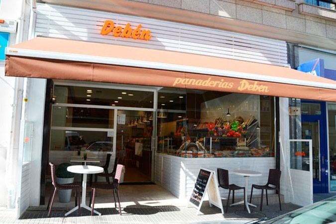 Una panadería con mesas y sillas bajo un toldo.